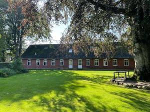 a red brick building with a tree and a bench at Wohnung in Salling in Buksager