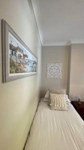 ein Schlafzimmer mit einem weißen Bett mit einem Bild an der Wand in der Unterkunft Gatelodge - Charming 2-Bed Cottage, Exmouth - Sleeps 3 in Exmouth + 45 Fotos