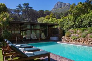 a swimming pool with lounge chairs and a house at Camps Bay Retreat Hotel in Cape Town