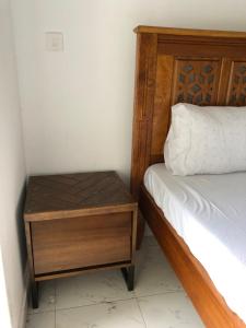 a bed with a wooden bed frame and a wooden nightstand at Queens Luxury Studio Mombasa in Mombasa