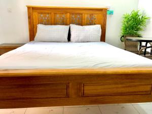 a wooden bed with white sheets and pillows on it at Queens Luxury Studio Mombasa in Mombasa +6 photos
