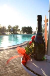 Una botella de vino sentada en una mesa junto a una piscina en Agriturismo Le Rose, en Pescia Romana