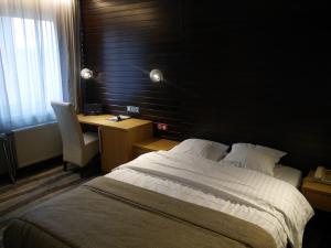 a bedroom with a bed and a desk and a chair at Hotel Maxim in De Panne