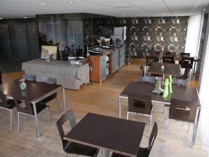 ein Restaurant mit Holztischen und -stühlen und einer Küche in der Unterkunft Hotel Maxim in De Panne