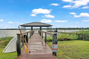 a wooden boardwalk leading to a gazebo on a lake at Nature's Nest Lake House in Lake Wales