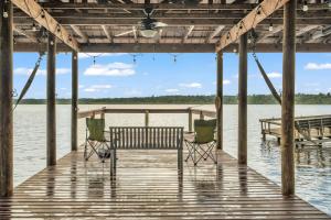 a dock with two chairs and a bench on the water at Nature's Nest Lake House in Lake Wales