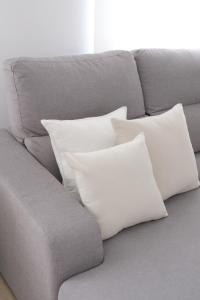 een grijze bank met vier witte kussens erop bij Corazón Cuatro in Jaén