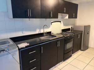 a kitchen with black cabinets and a sink and a refrigerator at APARTAMENTO cerca al UNICO in La Victoria +9 photos