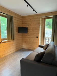a living room with a couch and a flat screen tv at Il Castello nel Bosco, appartamento Torrente in Champorcher