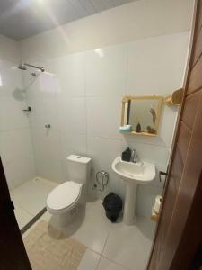 a white bathroom with a toilet and a sink at Temporada BHS Quarto 2 in Barreirinhas