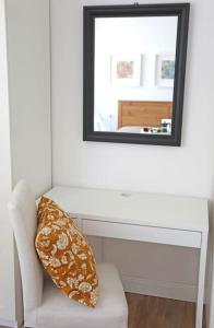 Un espejo en una pared encima de una silla blanca con una almohada. en Appartamento San Donato, en Florencia 18 fotos más