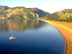 a boat in the water next to a beach at Bayrams Tree Houses in Olympos
