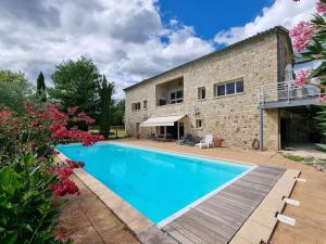 a swimming pool in front of a house with flowers at Les Vignes de Pagès - Villa de Standing in Lablachère