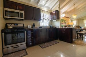 曼米湾Drax Hall-Near Ocho Rios-King Bed-Pool-BBQ Grill-Gated Complex-Free Parking-Free Wifi 100Mbps的配有木制橱柜和炉灶烤箱的厨房