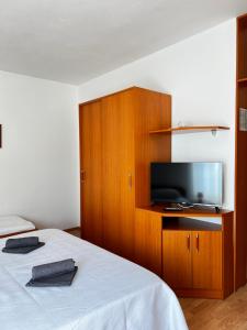 a bedroom with a bed with a tv and a cabinet at Family Majčica - villa Malo Misto in Klek