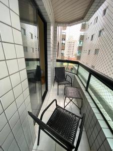 einen Balkon mit zwei Stühlen und einer Bank darauf in der Unterkunft Apto Moderno com Churrasqueira Gourmet, apenas 150m da Praia in Praia Grande
