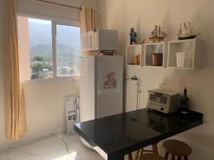 a kitchen with a refrigerator and a table with a microwave at Riviera Massaguaçu in Massaguassu