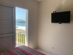 a bedroom with a large window with a flat screen tv at Riviera Massaguaçu in Massaguassu