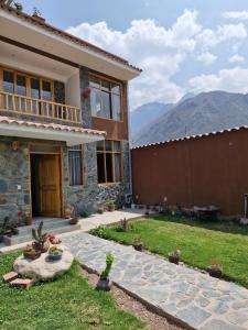 a house with a patio and a yard with mountains at Hostal Inti Urubamba in Urubamba