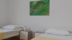 two beds in a room with a painting on the wall at Apartman EXCELLENT - Kuća za odmor u Županji -natkriveno parkirno mjesto in Županja