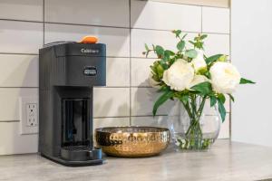 a coffee maker and a bowl of flowers on a counter at 2BR Cozy Suite w Fireplace! FREE Banff Pass, Parking, Netflix! Enjoy Yoga Classes or Plan Your Golf Trip! in Calgary +30 photos