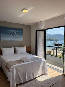 a bedroom with a white bed with a view of the ocean at Pousada do Canto in Abraão