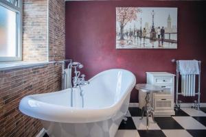 a bathroom with a white tub and a red wall at Bryn View – 5 Bedroom Holiday Home – Oxwich in Oxwich +73 photos