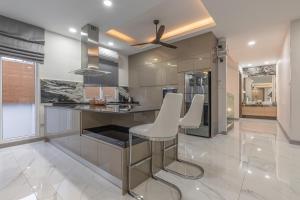 una cocina con barra con taburetes blancos en 芭提雅21航站楼附近8卧9卫轻奢现代别墅带独立歌房, en Norte de Pattaya
