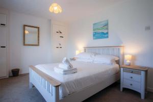 a bedroom with a bed with white sheets and a mirror at Channel View – 3 Bedroom House - Rhossili Bay in Oxwich
