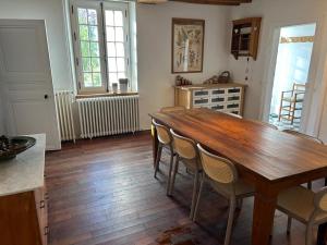 ein Esszimmer mit einem Holztisch und Stühlen in der Unterkunft Maison de campagne familiale in LʼHabit