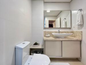 a white bathroom with a sink and a toilet at Apartamento Villaggio Del Veneto 1 dorm by Achei in Canela +22 photos