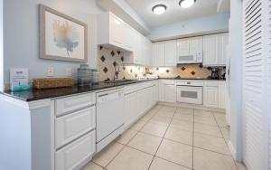 a kitchen with white cabinets and black counter tops at FL-Beach Colony East E3B condo in Pensacola