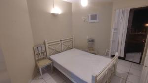a bedroom with a bed and a chair and a window at Apartamento Largo dos Coqueiros in Riviera de São Lourenço +27 photos