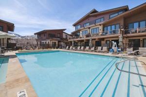 a large swimming pool at a hotel with chairs at One Riverfront Condo 204 by East West Hospitality in Avon