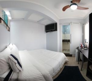 a bedroom with a white bed and a ceiling fan at Santo Antônio Hotel Ltda in Angatuba