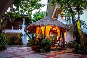 a building with a straw umbrella and some plants at Papierus Pensionne in Kalibo
