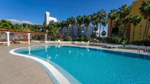 a large swimming pool with chairs and palm trees at El Bungalow in Playa Fañabe