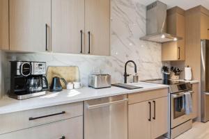 a kitchen with white marble walls and wooden cabinets at One Riverfront Condo 108 by East West Hospitality in Avon