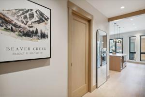 a hallway with a door and a sign on a wall at One Riverfront Condo 108 by East West Hospitality in Avon