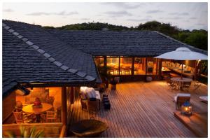 una terraza con mesas, sillas y sombrilla en Pousada Tutabel, en Trancoso