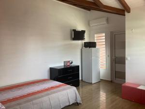 a bedroom with a white refrigerator and a black dresser at Residence l oiseau des iles in Grand-Bourg