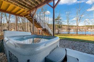 Un jacuzzi situado debajo de un pabellón con vistas a un lago. en Lakefront Home with Private Beach Access & Hot Tub, en Milton