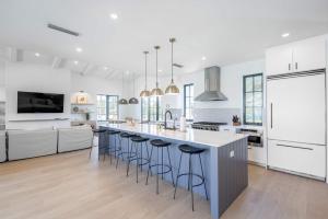 a white kitchen with a large island with bar stools at Brand New Build Larkshine House - Pool in Key West