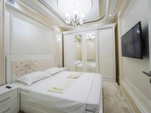 a white bedroom with a bed and a television at CityCenter Apartment in Samarkand