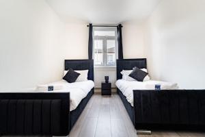 two beds in a room with a window at LUX 2BDR Flat By Luton Station, Airport, City Centre - 30min to King's X St Pancras International in Luton