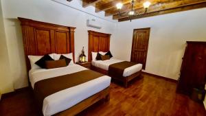 two beds in a room with wooden floors at Hotel Boutique Pedregal in Coatepec