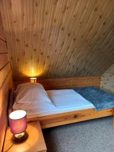 a wooden bed in a wooden room with a lamp at Bieszczady Domek Letniskowy in Polańczyk