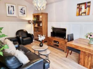 a living room with a couch and a television at Charming Detached Cottage Near John Radcliffe Hospital Free Parking Self check-in in Oxford