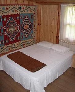 1 dormitorio con 1 cama con sábanas blancas y ventana en Bayrams Tree Houses en Olympos