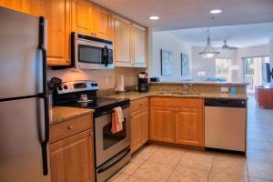 a kitchen with wooden cabinets and a stove top oven at Coastal Serenity in St Pete Beach